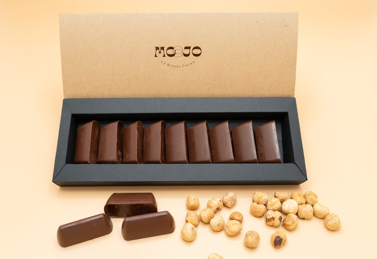 Offene MOOJO-Schachtel mit aufgereihten Giandujotti, dazu Haselnüsse
