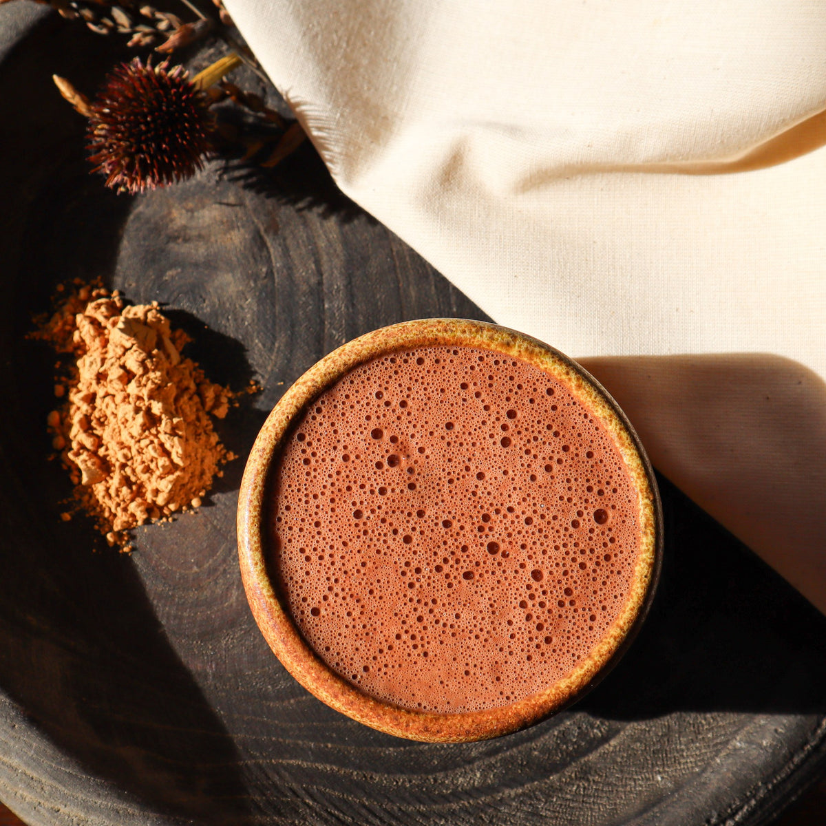 Tasse de cacao et poudre de maca sur un plateau en bois sombre, vue du dessus