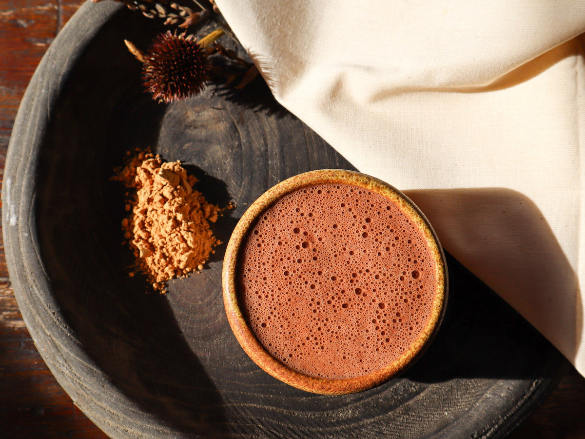 Poudre de maca, tasse de cacao et lin écru sur un plateau en bois