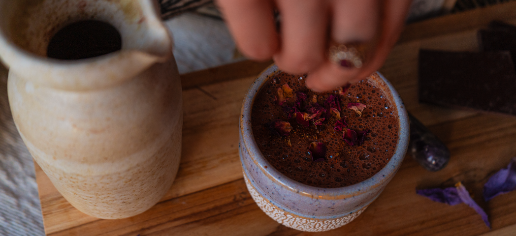 Main saupoudrant des pétales de rose sur une tasse