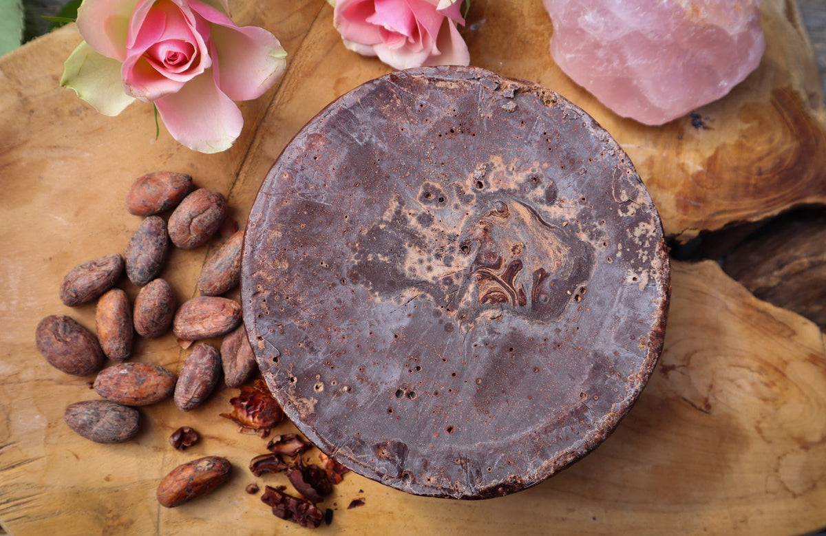 Pastilla redonda de cacao puro sobre una tabla de madera, con granos de cacao y una rosa · Guatemala Tuq'tuquilal