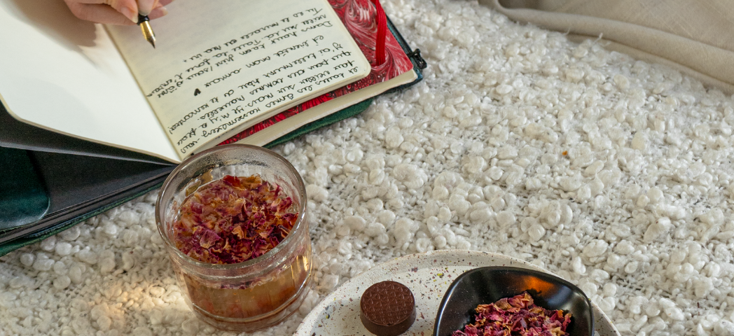 Infusion de pétales de rose de Damas, carnet ouvert et bouchée de chocolat