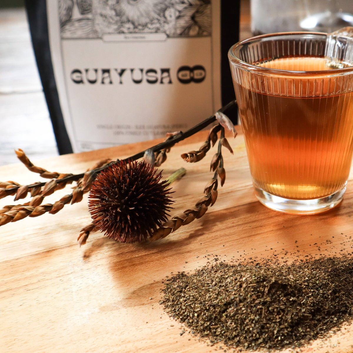 Bag of guayusa, a cup of amber infusion and ground leaves