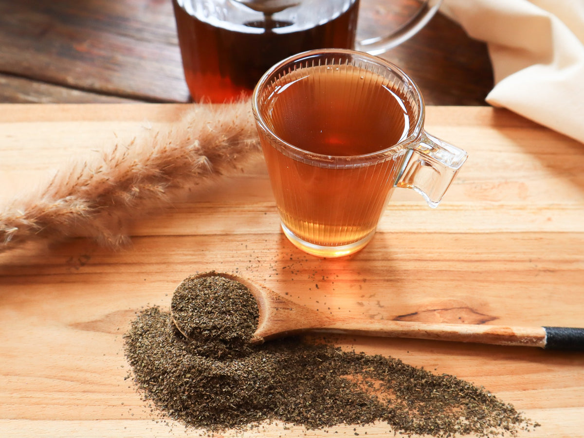 Guayusa infusion and a spoon of ground leaves on a wooden board